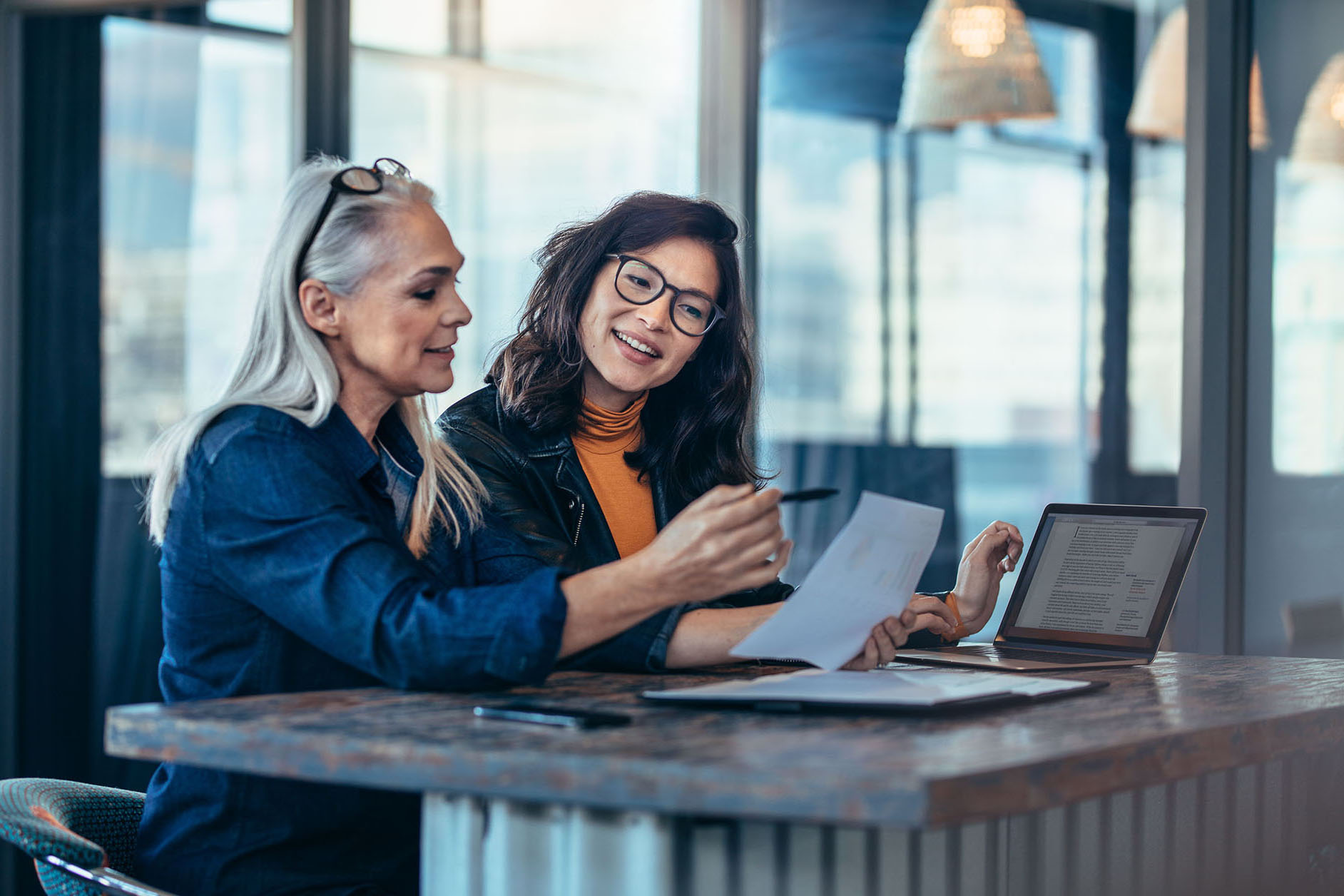 Two women analyzing documents at office